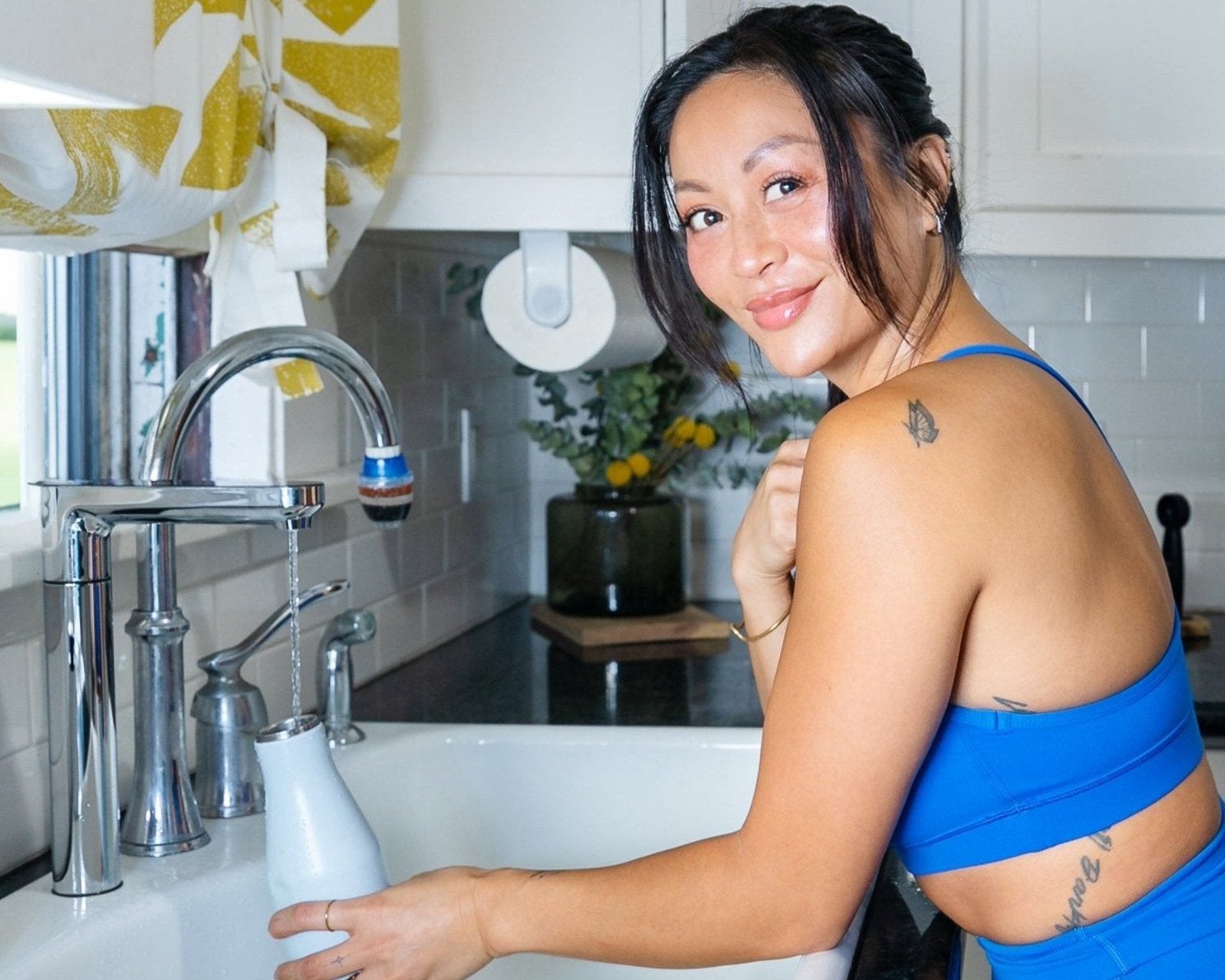 girl in blue work out gear filling reusable water bottle using a reverse osmosis system